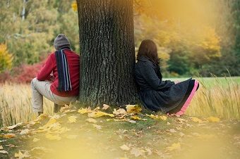 Two young people sitting under tree