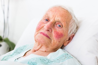 A portrait of a blue eyed elderly woman laying in bed.